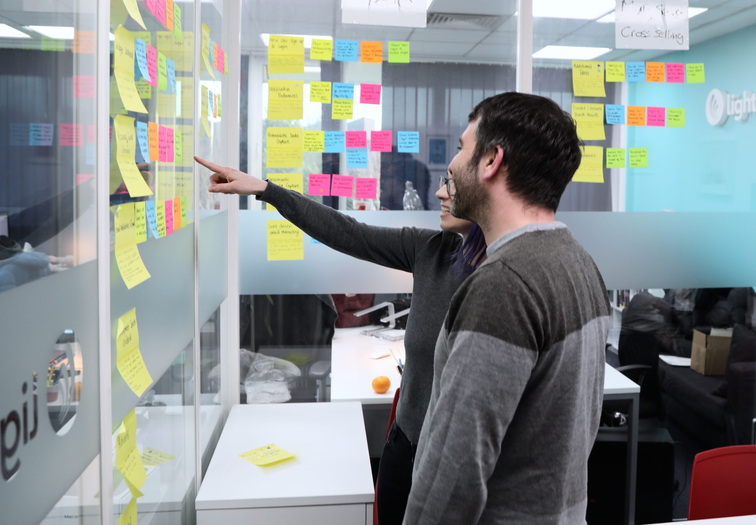 Team members Hannah and Victor looking at post-it notes in the meeting room